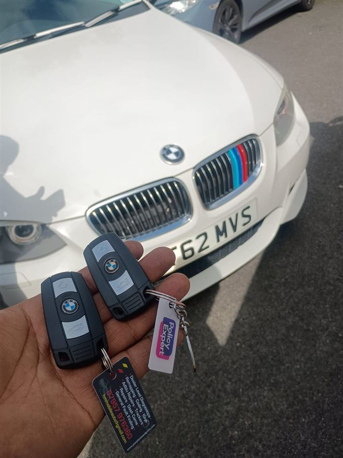 Two replacement BMW keys held in front of the car they were programmed to
