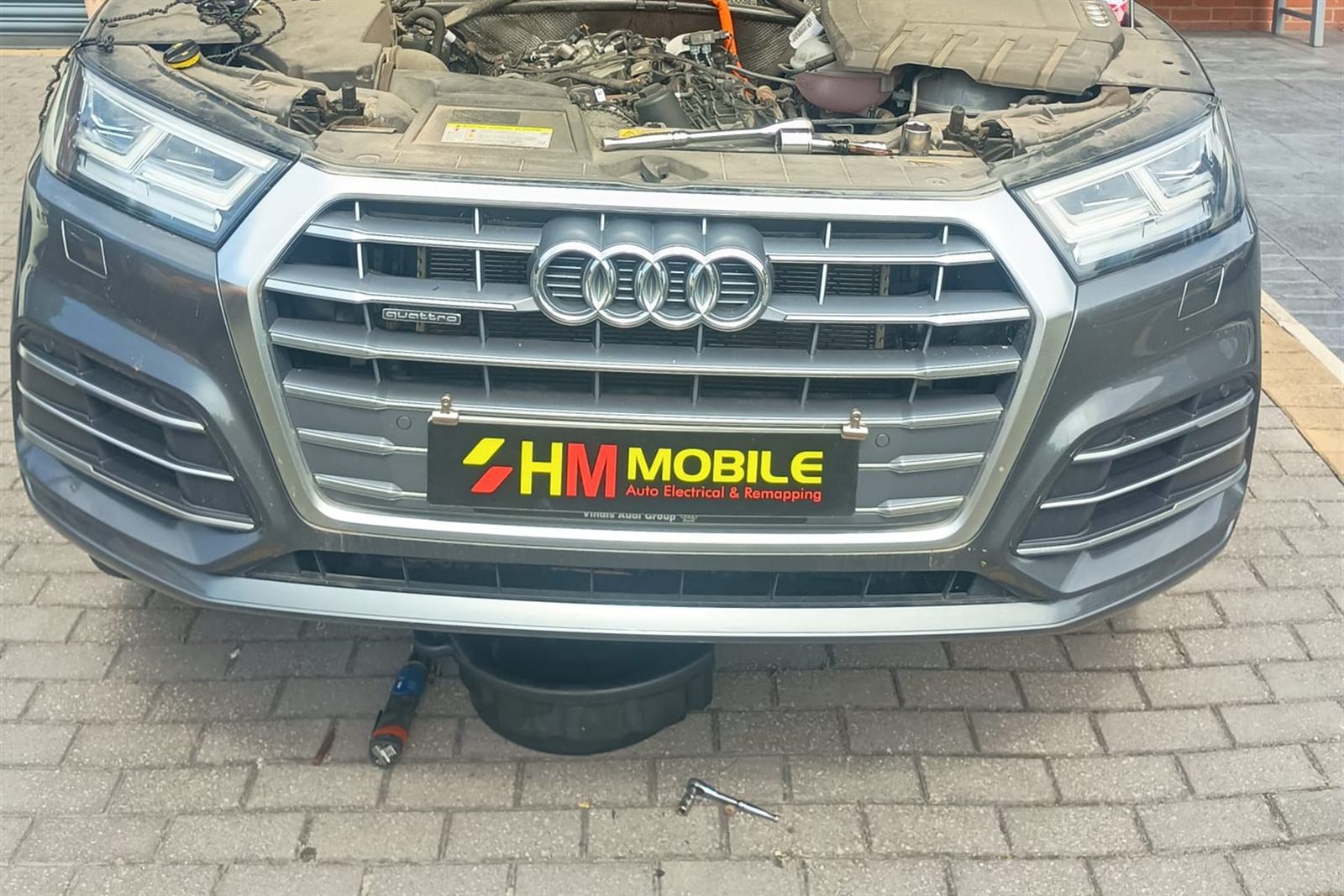 Audi Q5 on a block paved driveway with the bonnet up and an HM Mobile trade plate fitted to the grille