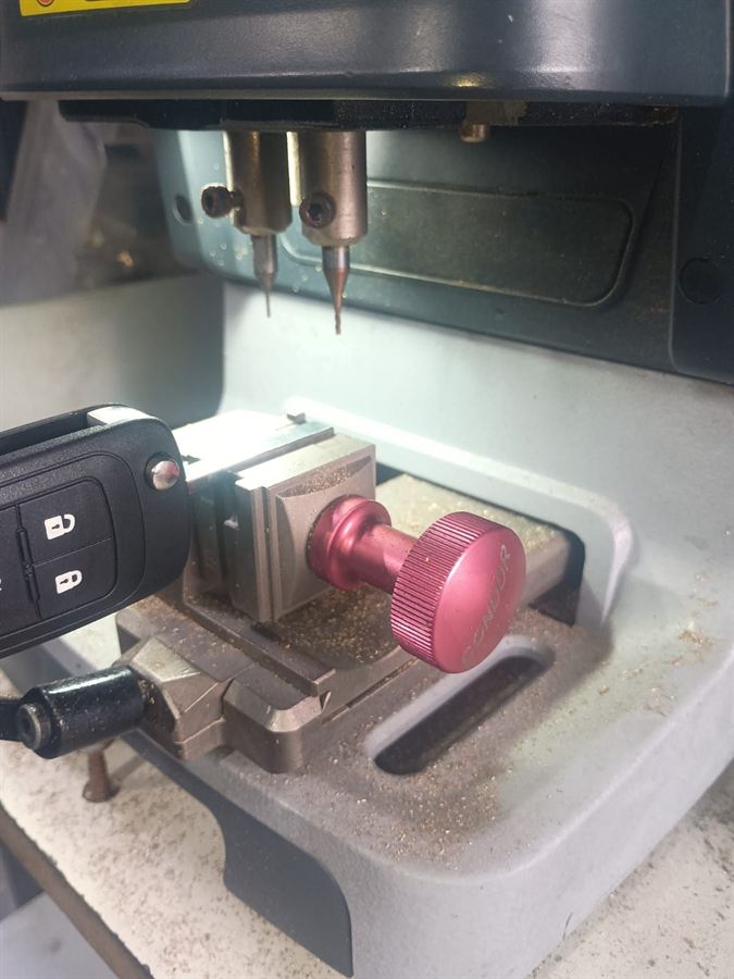 Car key clamped in a key cutting machine being cut to code