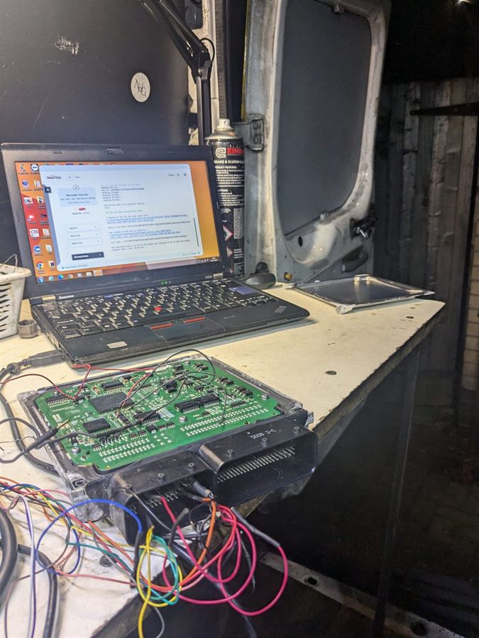Mercedes Sprinter ECU opened on the workbench in the back of the van, wired to a laptop